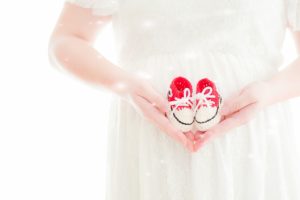 赤ちゃんの靴を持った妊婦